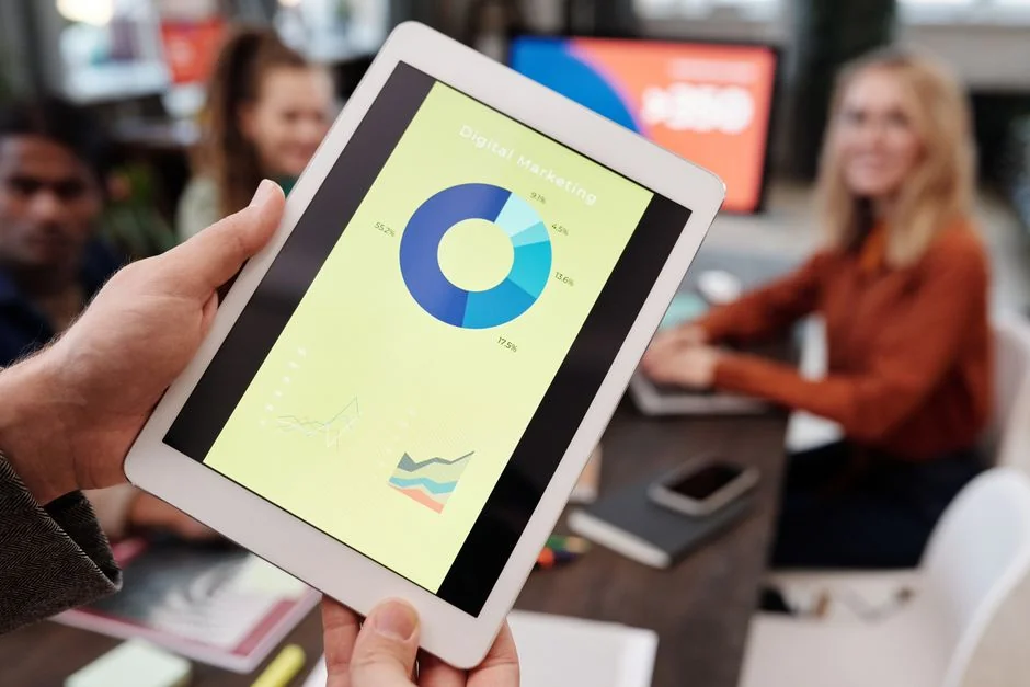 Person analyzes stock data with a smartphone and laptop, indoors.