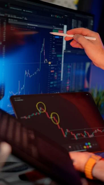 Hands typing on a laptop with cryptocurrency charts and smartphone display in view, focusing on digital finance.